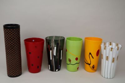 Plusieurs tasses de différentes couleurs sont alignées sur une surface blanche.