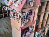 une maison de poupées en bois sur laquelle sont posés de nombreux animaux en peluche