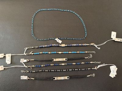 quatre bracelets différents, munis d'étiquettes, posés sur un fond noir