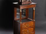 a clock on top of a cabinet with a drawer underneath it
