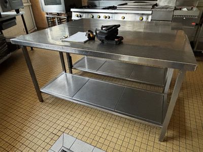 une grande table en acier inoxydable au milieu d'une cuisine