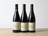 trois bouteilles de vin posées sur une table en bois