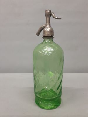 une bouteille en verre vert munie d'une poignée en métal, posée sur une table