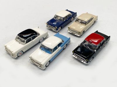 plusieurs petites voitures sont alignées sur une surface blanche