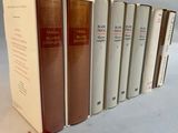 several books are lined up in a row on a white surface