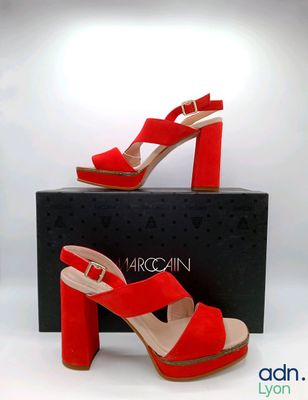 Les chaussures rouges se trouvent sur la boîte à côté de la boîte noire.