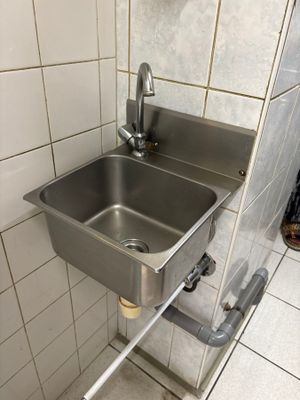 un évier en acier inoxydable dans le coin d'une salle de bains