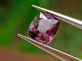 quelqu'un tient une pince dans laquelle est sertie un diamant rose