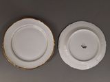 two white plates with gold rims are sitting on a table
