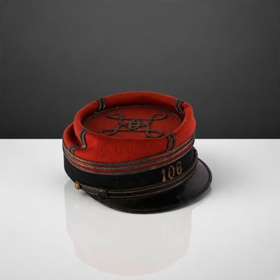 une image représentant un chapeau rouge et noir posé sur une table blanche
