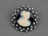 une broche en camée noir et blanc représentant le profil d'une femme, entouré de diamants