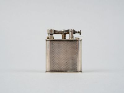 un vieux briquet en argent posé sur une surface blanche
