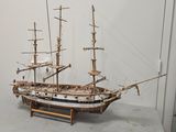 a wooden model of a ship on display in a glass case