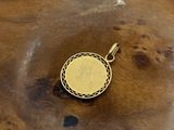an image of a gold pendant sitting on top of a wooden table