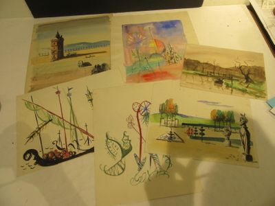 many drawings on a table with a laptop on top of it