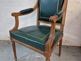 a green leather chair with a wooden frame on the floor