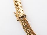 an image of a close up of a gold bracelet on a white surface