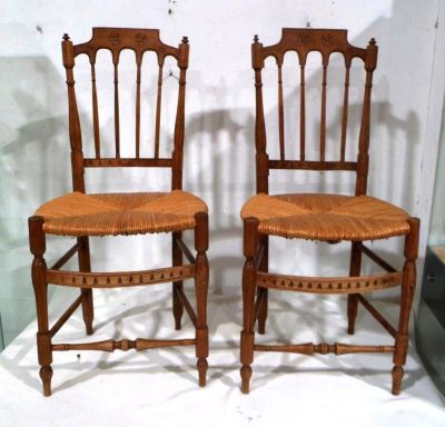 une paire de chaises anciennes en bois avec des assises en osier, exposées