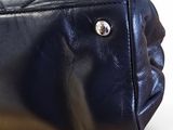 black leather purse with gold hardware on top of white surface