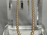 un collier de perles exposé sur un socle en verre transparent