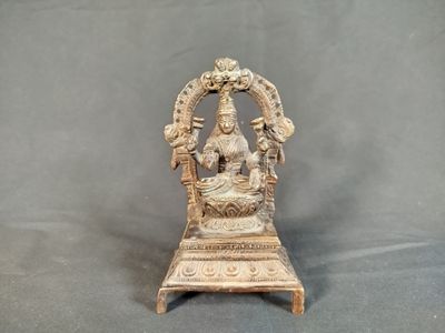 une statue représentant une femme assise sur une chaise