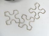 four pieces of metal on a white surface next to a pair of scissors