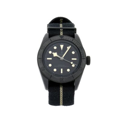 une photo d'une montre au cadran noir, montée sur un bracelet noir