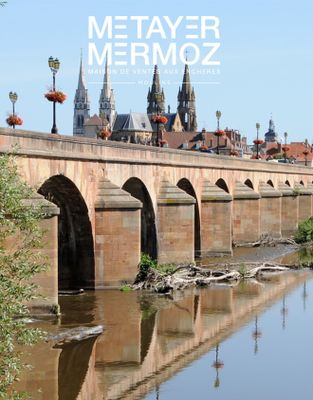 une photo d'un pont enjambant une rivière, avec un bâtiment en arrière-plan