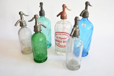 quatre bouteilles en verre de couleurs différentes, munies d'un bec verseur en métal