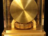 a gold clock in a glass case on a black surface