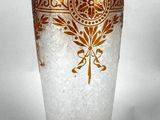 a glass vase with a gold design on it