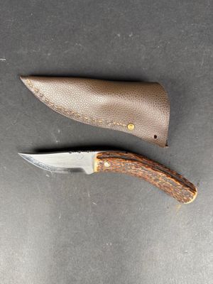 a knife and sheath on the table next to each other