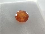 a close up of an orange diamond on a white surface