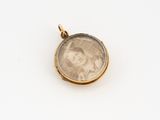 a close up of a gold pendant with a picture of a woman