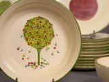 a plate with a tree painted on it next to a bowl