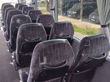 rows of seats on a bus with a view of a parking lot