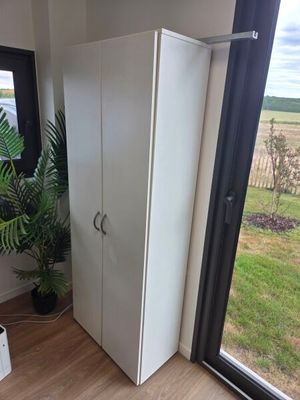une armoire blanche dans un coin d'une pièce dotée d'une grande fenêtre