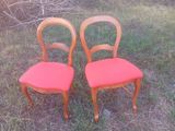 deux chaises en bois aux assises rembourrées de rouge, posées dans l'herbe