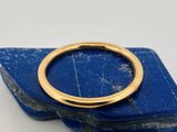 un gros plan d'une bague en or posée sur une pierre bleue