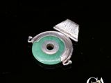 une photo d'un pendentif en argent et en jade orné d'un œil vert