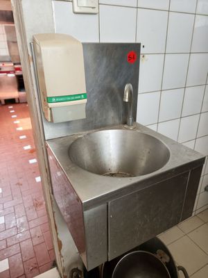 a sink in the middle of a kitchen with a pot on the floor