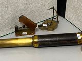 un télescope doré posé sur une étagère en verre, à côté d'un briquet
