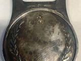 an antique silver plate with a bottle opener on top of it