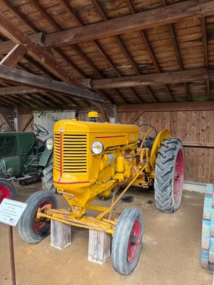 un gros tracteur jaune garé à l'intérieur d'une grange