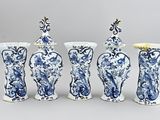 quatre vases bleus et blancs sont alignés sur un fond gris