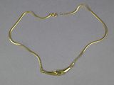 a close up of a gold necklace with a green stone on it