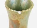 a green vase with a design on it on a white surface