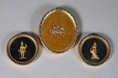 trois broches dorées et noires représentant un homme à cheval et une femme à cheval