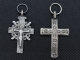two silver cross charms on a black background