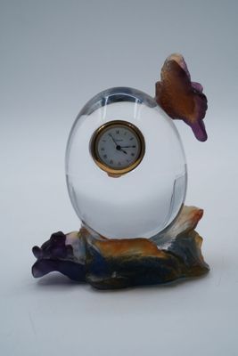 une petite horloge en verre posée sur un rocher